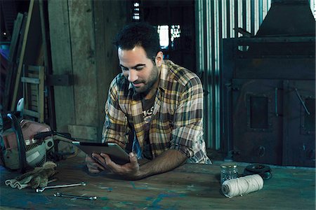 rusty tools - Man searching internet for instructions to repair broken chainsaw Stock Photo - Premium Royalty-Free, Code: 632-08698323