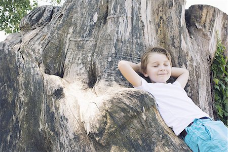simsearch:632-05553524,k - Boy leaning against big tree trunk Stock Photo - Premium Royalty-Free, Code: 632-08698415
