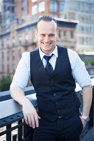 simsearch:632-08886522,k - Businessman standing on balcony, smiling, portrait Stock Photo - Premium Royalty-Free, Code: 632-08886520