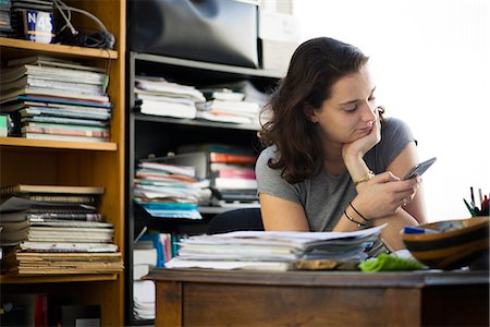 Office worker taking break to browse social media using smartphone Stock Photo - Premium Royalty-Free, Code: 632-08886731