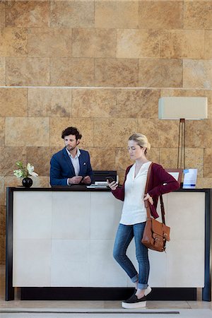 recepção - Woman looking at smartphone while waiting at reception desk Foto de stock - Royalty Free Premium, Número: 632-08886781