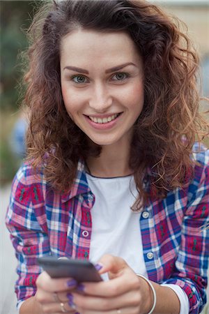 Young woman using smartphone, smiling, portrait Stock Photo - Premium Royalty-Free, Code: 632-08886841