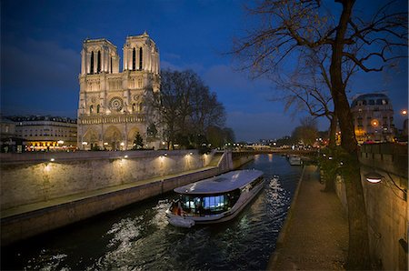 A pleasure boat moves past Notre Dame Cathedral on the Seine River at twilight, Paris, France Foto de stock - Sin royalties Premium, Código: 632-08886886