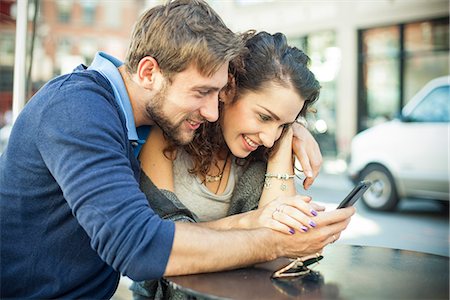 simsearch:632-08993683,k - Couple sitting outdoors together, looking at smartphone Fotografie stock - Premium Royalty-Free, Codice: 632-08886995