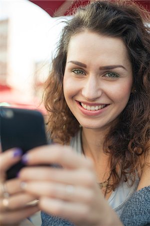 simsearch:632-09021472,k - Young woman using smartphone, smiling, portrait Stock Photo - Premium Royalty-Free, Code: 632-08886993