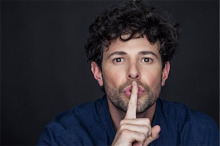 simsearch:632-08993526,k - Man silencing with finger held to lips Stock Photo - Premium Royalty-Free, Code: 632-08993404