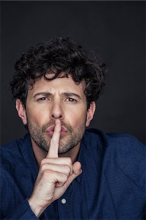 simsearch:632-08993526,k - Man silencing with finger held to lips Stock Photo - Premium Royalty-Free, Code: 632-08993405