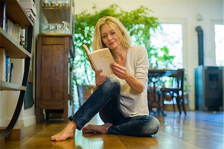 sitting holding legs up - Mature woman relaxing on floor with book at home Stock Photo - Premium Royalty-Free, Code: 632-08993633