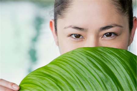 simsearch:632-08993453,k - Young woman holding large leaf in front of her face Stock Photo - Premium Royalty-Free, Code: 632-09021562