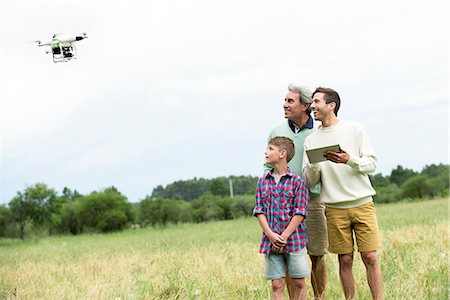 digital tablet and young adult laughing - Multi-generation family playing with drone in field Stock Photo - Premium Royalty-Free, Code: 632-09021573