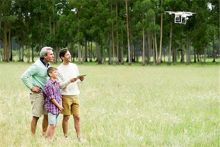 Man flying remote control drone in open field while older man and boy watch Photographie de stock - Premium Libres de Droits, Code: 632-09021587