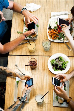 Diners using smartphones in restaurant, cropped overhead view Stock Photo - Premium Royalty-Free, Code: 632-09039783
