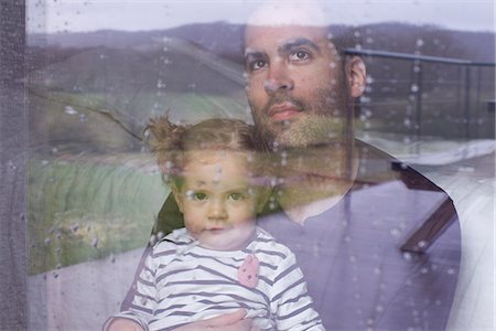 Man with young child looking through window watching rain fall Stock Photo - Premium Royalty-Free, Code: 632-09039828