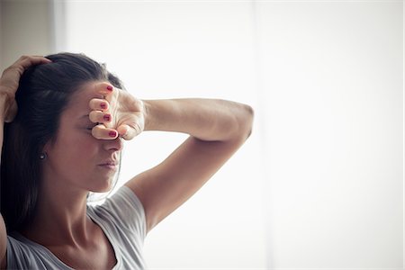 simsearch:6108-08725286,k - Young woman holding one hand on forehead Stock Photo - Premium Royalty-Free, Code: 632-09039886