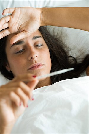 simsearch:632-09039999,k - Woman lying in bed taking temperature with thermometer Stock Photo - Premium Royalty-Free, Code: 632-09039892