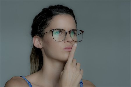 simsearch:632-07539867,k - Young woman looking away in thought with finger held to lips Photographie de stock - Premium Libres de Droits, Code: 632-09039978