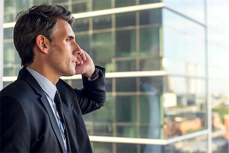 Man looking through window in high rise building Stock Photo - Premium Royalty-Free, Code: 632-09140205