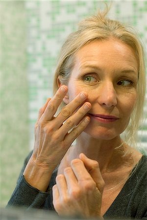 Mature woman scrutinizing her face in bathroom mirror Photographie de stock - Premium Libres de Droits, Code: 632-09140313