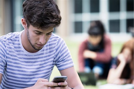 students campus phones - Young man looking at smartphone outdoors Stock Photo - Premium Royalty-Free, Code: 632-09157982