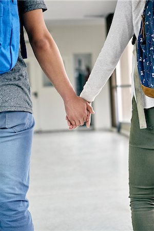 Young couple holding hands while walking in school corridor, cropped rear view Stock Photo - Premium Royalty-Free, Code: 632-09158128