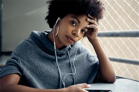 Young woman listening to earphones, holding head, portrait Stock Photo - Premium Royalty-Free, Code: 632-09158139