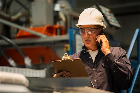 person on phone with clipboard - Factory worker using mobile phone in factory Stock Photo - Premium Royalty-Free, Code: 632-09162736