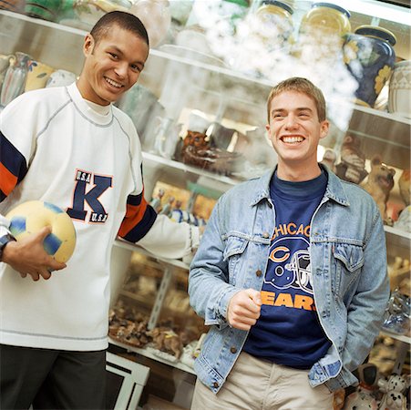 simsearch:632-01137036,k - Young men leaning against store window, smiling, facing camera. Foto de stock - Sin royalties Premium, Código: 632-01137801