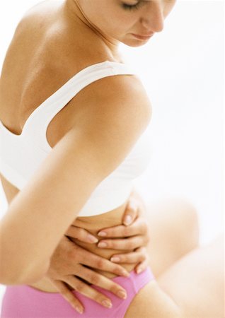 Close Up of Woman in Underwear Holding Stomach in Pain Stock Photo