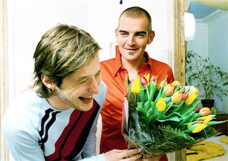 Two men smiling and laughing, one holding bouquet of flowers, portrait. Stock Photo - Premium Royalty-Free, Code: 632-01144052