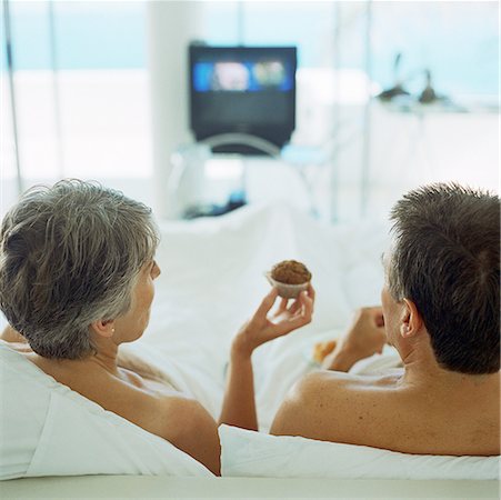 Mature couple in bed, woman holding muffin, rear view Stock Photo - Premium Royalty-Free, Code: 632-01144265