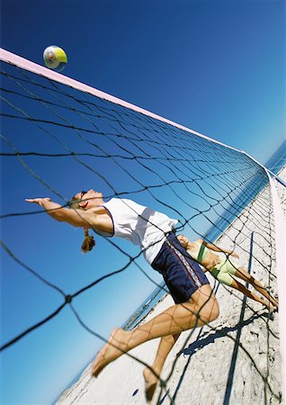 Two young women playing beach volleyball, one in mid-air. Stock Photo - Premium Royalty-Free, Code: 632-01144695