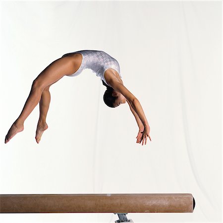 Young female gymnast over balance beam, mid-air, side view Stock Photo - Premium Royalty-Free, Code: 632-01145062