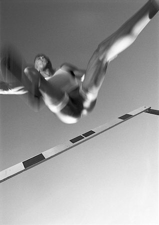 fitness black and white - male athlete jumping hurdle, low angle view, blurred motion, b&w Foto de stock - Sin royalties Premium, Código: 632-01145079