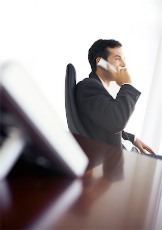 Businessman at desk using phone, side view Stock Photo - Premium Royalty-Free, Code: 632-01146030