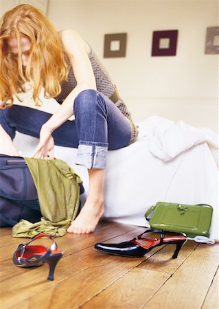 Woman sitting on bed looking through bag. Stock Photo - Premium Royalty-Free, Code: 632-01147640