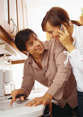 Woman on phone leaning on man writing. Stock Photo - Premium Royalty-Free, Code: 632-01147777