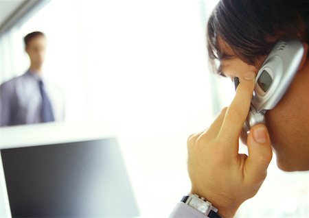 simsearch:695-03381633,k - Businessman on cell phone facing computer, side view, close-up Stock Photo - Premium Royalty-Free, Code: 632-01147825