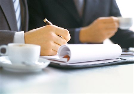 pen two hands - Businessman writing near businessman holding cup Stock Photo - Premium Royalty-Free, Code: 632-01147857