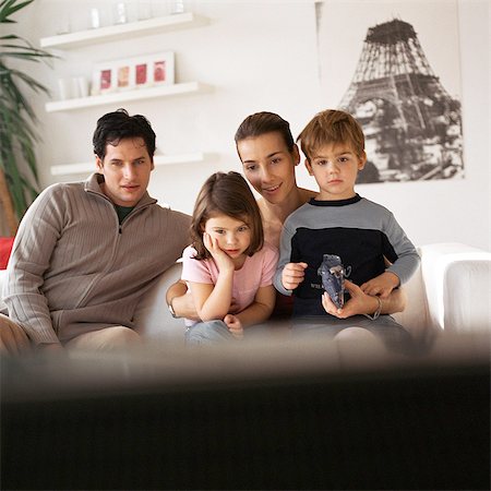 simsearch:632-01147960,k - Family sitting on the couch, rear view of tv in foreground, blurred Stock Photo - Premium Royalty-Free, Code: 632-01147970