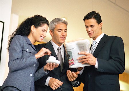 Group of business people looking at newspaper together, waist up, low angle view Stock Photo - Premium Royalty-Free, Code: 632-01148057