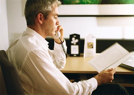 Businessman talking on phone, looking at paper, side view, close-up Stock Photo - Premium Royalty-Free, Code: 632-01148066