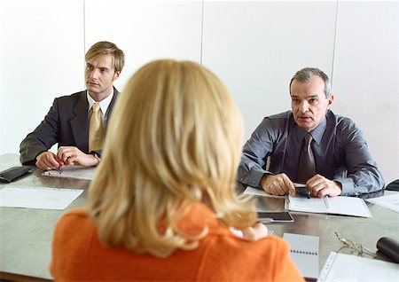 Businessmen and businesswoman sitting at table, woman's back to camera. Stock Photo - Premium Royalty-Free, Code: 632-01148329