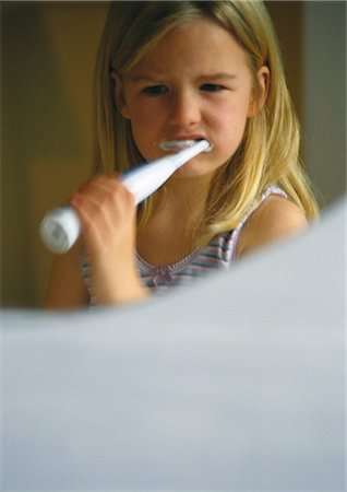 Little girl brushing teeth with electric toothbrush, focus on reflection in mirror Stock Photo - Premium Royalty-Free, Code: 632-01148739