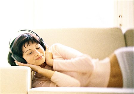 simsearch:632-01149081,k - Woman lying on sofa, listening to headphones Stock Photo - Premium Royalty-Free, Code: 632-01149041