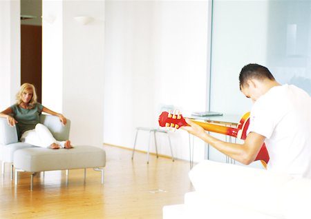 Man playing guitar, rear view, woman sitting in armchair Stock Photo - Premium Royalty-Free, Code: 632-01149062