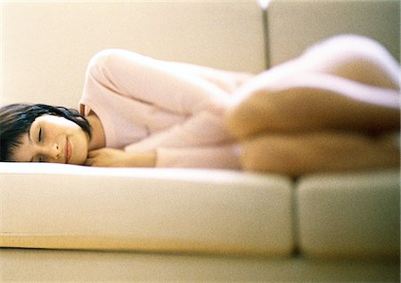 Woman lying curled up on sofa, eyes closed Stock Photo - Premium Royalty-Free, Code: 632-01149072