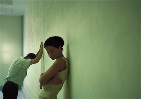 erreur de communication - Femme avec le dos contre le mur, bras repliés, l'homme en se penchant libèrerai contre le mur de fond Photographie de stock - Premium Libres de Droits, Code: 632-01149193