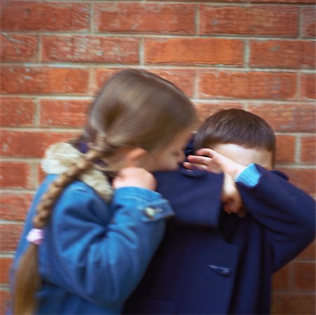Girl trying to kiss boy, boy covering face with arms, blurred Stock Photo - Premium Royalty-Free, Code: 632-01149432
