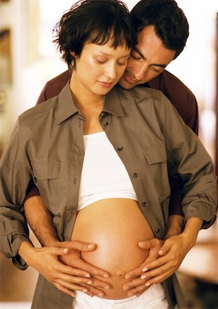 Man touching pregnant woman's stomach from behind Stock Photo - Premium Royalty-Free, Code: 632-01140052