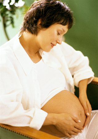 simsearch:633-05401926,k - Femme enceinte avec les mains sur le ventre, regardant vers le bas Photographie de stock - Premium Libres de Droits, Code: 632-01140090
